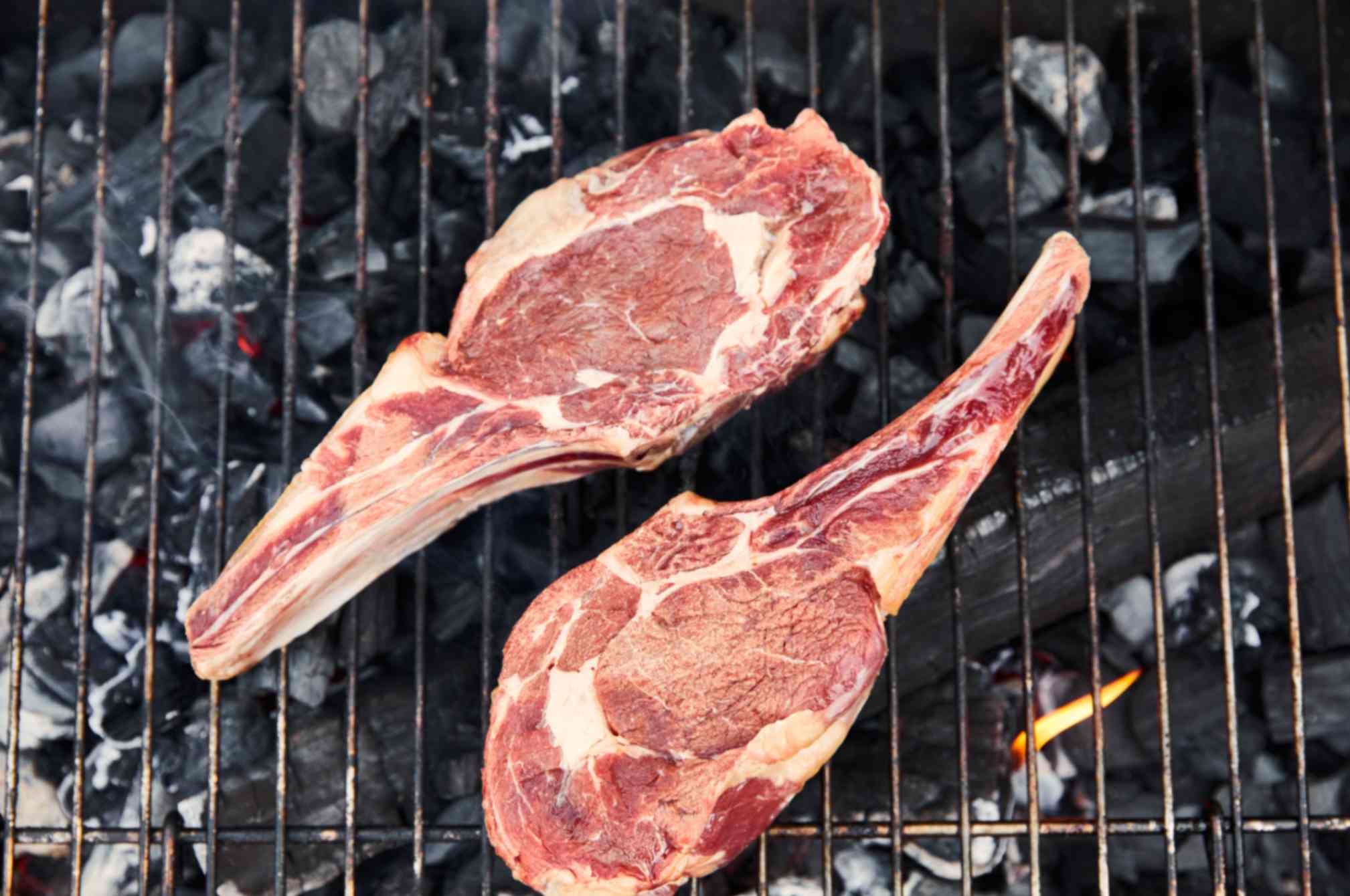 Halal lamb chops searing on a two-zone charcoal grill, charred outside and cooked evenly inside