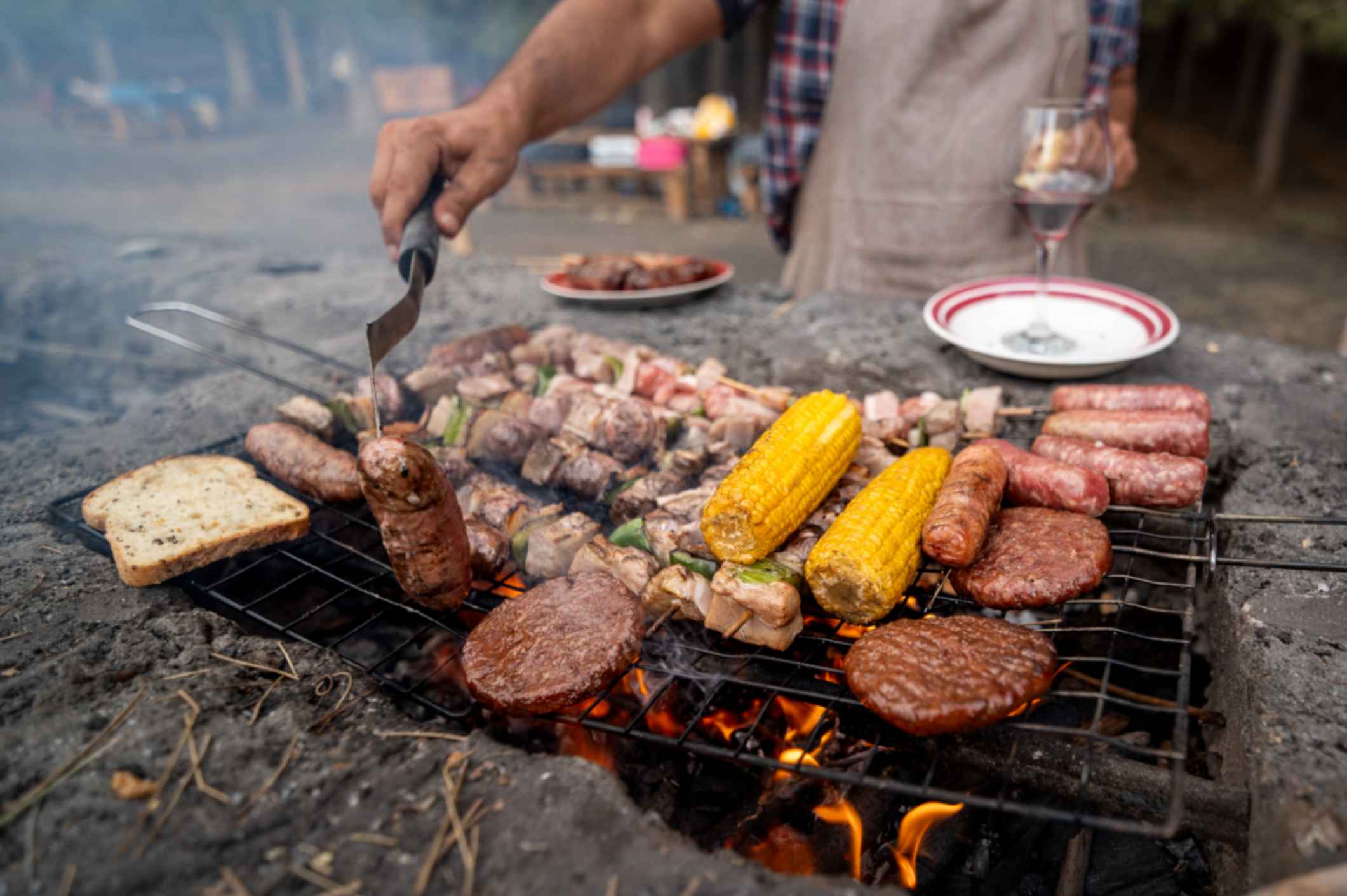 A halal summer BBQ spread with marinated chicken, lamb chops, kebabs and burgers grilling over coals
