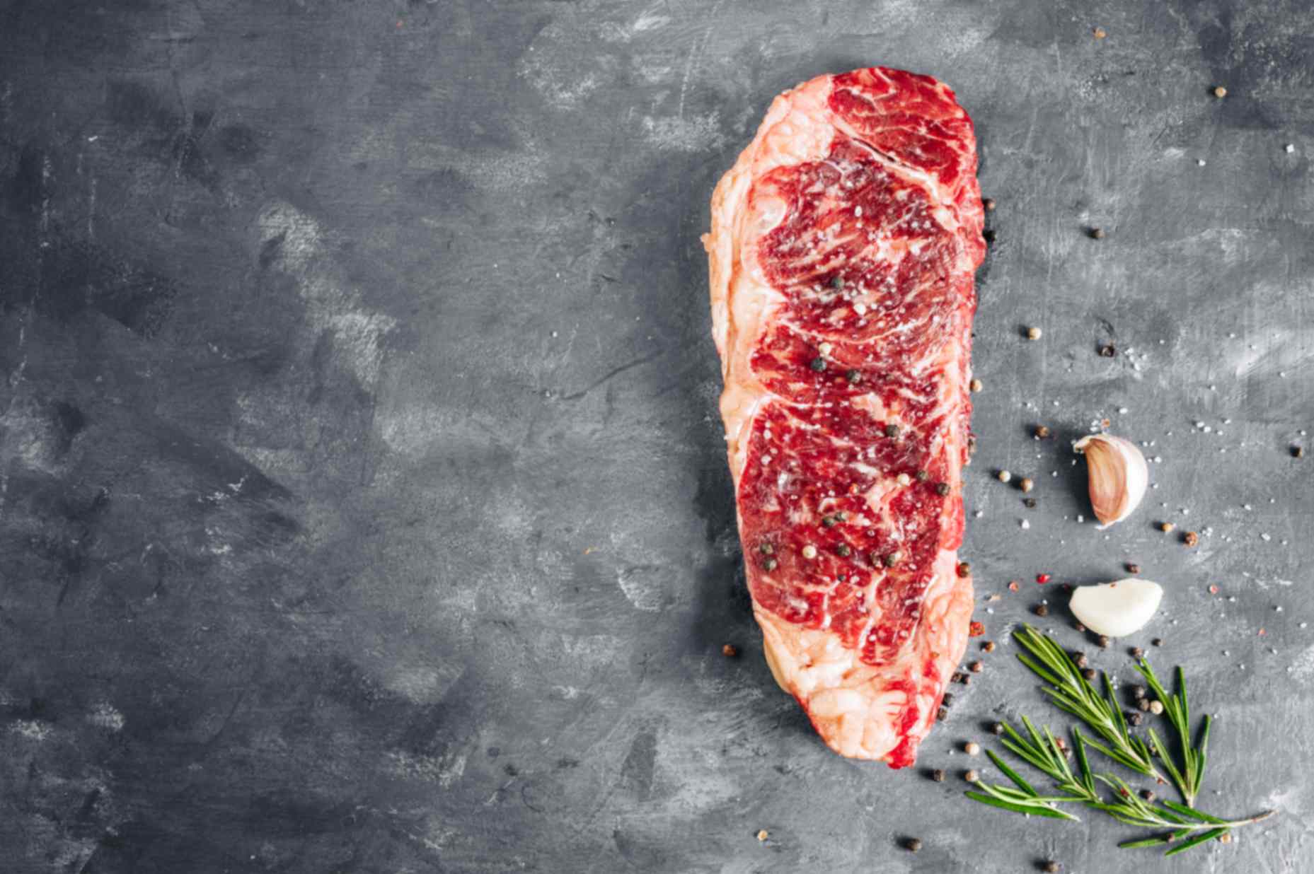 Close-up of a well marbled halal ribeye steak beside a leaner cut, showing intramuscular fat