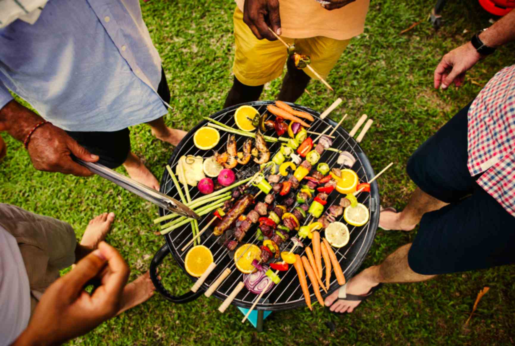 A halal summer BBQ spread with marinated chicken, lamb cutlets and kebabs grilling over coals.